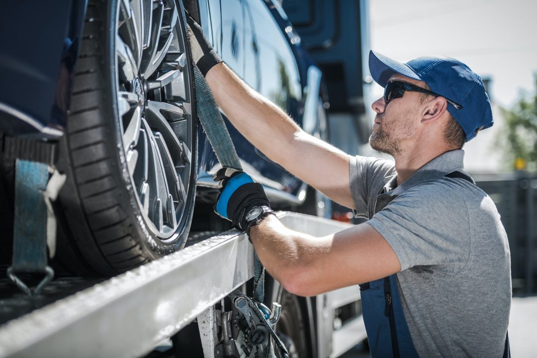 towing truck driver securing transported vehicle.jpg